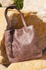 Bolso shopper Sagali de cuero vacuno color marrón, con diseño de paneles geométricos, asas largas y detalle de fleco decorativo en el lateral.