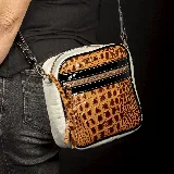 Bandolera de cuero vacuno color tostado y blanco con estampado de cocodrilo. Tiene correa larga ajustable y removible, bolsillo con cierre en la tapa externa y forro interior de tela con bolsillo con cierre.