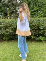 Camisa blanca de lino con mangas largas y corte holgado. Presenta un bloque de color marrón en la parte inferior.