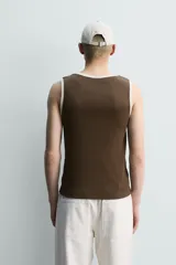 Camiseta sin mangas slim fit color crema, confeccionada en tejido de algodón elástico, con cuello redondo y ribetes en contraste color beige.