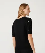 Blusa de punto negra con escote redondo, manga corta y apliques de corazones dorados.