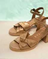 Sandalia de cuero vacuno color dorado, con taco cuadrado y tira con hebilla al tobillo.