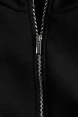 Campera negra de efecto neopreno, con cuello chimenea, cierre frontal completo y hombros caídos. Presenta un diseño holgado con pliegues en el bajo y mangas largas.