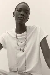 Pack de tres collares de diferentes largos, compuestos por cordones oscuros, piezas metálicas labradas, abalorios de colores, perlas y diversos charms colgantes con aplicaciones de cristales y brillos.