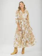 Vestido camisero midi de algodón con estampado floral en tonos rosados y blancos. Tiene cuello camisero, mangas 3/4, botones frontales, falda escalonada y cinturón fino.