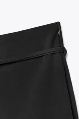 Falda pantalón de tiro medio en color blanco, con diseño minimalista y detalle de cinturón fino integrado con hebilla metálica. Cuenta con cierre lateral mediante cremallera oculta.