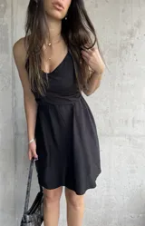 Vestido corto negro con breteles finos y escote cruzado.