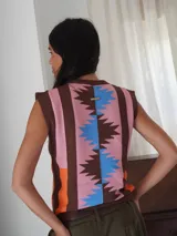 Chaleco sin mangas de tejido de punto con escote en V y diseño geométrico con rayas verticales en tonos marrón, naranja, rosa y celeste.
