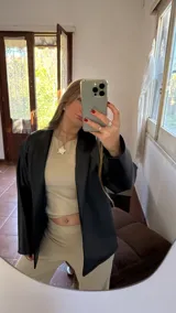 Blazer negro de cuero sintético con cuello solapa y corte estructurado.