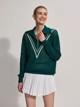 Sweater de punto verde oscuro con cierre dorado y cuello polo. Presenta un diseño en V blanco en el pecho.