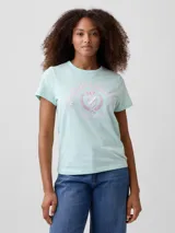 Remera de algodón color verde menta, de corte clásico con cuello redondo y mangas cortas. Presenta un estampado gráfico frontal en tonos rosados con la inscripción 'WEEKEND ATHLETICS GAP SINCE 1969' y un escudo central.