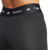 Calzas cortas deportivas Adidas Techfit, color negro, ajustadas al cuerpo con cintura elástica ancha que lleva el logo de Adidas y la palabra "TECHFIT" repetida. Presenta el logo de Adidas impreso en blanco en la pierna izquierda.