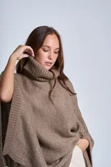 Poncho tejido color beige, con cuello alto y corte asimétrico.