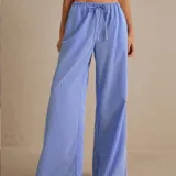 Pantalón palazzo celeste a rayas verticales blancas, de tiro alto y corte holgado.