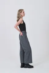 Pantalón de poliéster con estampado tartán en tonos grises y azules. Diseño de tiro medio, corte recto y ancho, con detalle de lazo ajustable en la cintura.