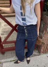 Jean 2 en 1 de color azul oscuro, con corte wide leg transformable a babucha mediante ajuste en los tobillos, tiro alto con cierre frontal de múltiples botones metálicos y bolsillos delanteros destacados.