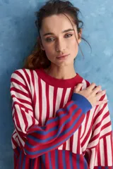 Sweater de tejido jacquard con diseño de rayas verticales en tonos rojo, blanco y azul. Presenta cuello redondo, hombros caídos y puños en contraste de color azul.