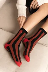 Medias de caña media con diseño de rayas verticales en color negro y bordó, con puntera y talón en color rojo vibrante. Incluye un pequeño bordado en la parte superior.