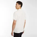 Remera polo blanca de piqué con cuello clásico, manga corta y cierre frontal con cremallera metálica.