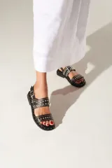 Sandalias negras de cuero con doble tira y tachas plateadas.