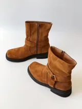 Bota corta de cuero color camel, con correa decorativa alrededor del tobillo y suela de goma negra.