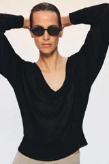 Jersey de punto negro con escote en V pronunciado, mangas largas con sisa caída y puños y dobladillo acanalados.