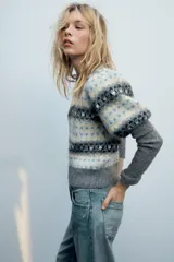 Jersey de punto con cuello redondo y mangas largas abullonadas, con diseño de jacquard geométrico en tonos grises, blancos y celestes.