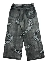 Jean baggy fit de tiro bajo en denim color negro con efecto lavado. Presenta bordados detallados en toda la prenda con motivos orgánicos y abstractos.
