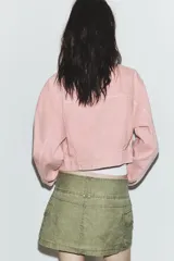 Cazadora de denim en color rosado, con cuello solapa, manga larga y cierre frontal con botones metálicos. Presenta bolsillos con solapa y botón en el pecho, además de trabillas en la cintura.