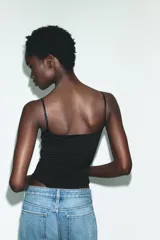 Body de escote recto con tirantes finos ajustables y cierre inferior con botones a presión.