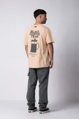 Remera de algodón con efecto lavado, color beige, de corte holgado y manga corta. Presenta un estampado pequeño en el pecho con la frase 'Coffee Break' y un estampado grande en la espalda.