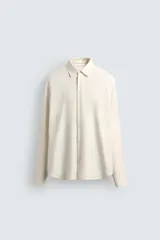 Camisa de corte regular fit confeccionada en una mezcla de algodón y lana. Presenta cuello solapa, manga larga con puños abotonados y cierre frontal con botones.