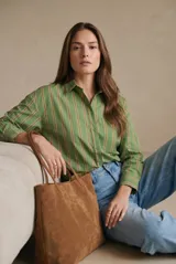 Camisa de corte oversize con estampado de rayas verticales en tonos verde, blanco y ocre. Presenta cuello clásico, cierre frontal con botones, bolsillo en el pecho y mangas largas con puños abotonados.