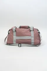 Bolso deportivo color rosa con detalles en beige y gris. Tiene doble asa de mano y correa de hombro ajustable. Cuenta con dos bolsillos frontales con cierre y logo de la marca en la esquina inferior derecha.