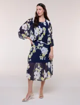 Conjunto de dos piezas en gasa azul marino con estampado floral en tonos blancos y amarillos, compuesto por un vestido midi sin mangas con forro y una capa ligera de mangas amplias.