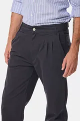 Pantalón de vestir color verde oliva, de corte recto, con bolsillos laterales y traseros. Se ajusta a la cintura con cinturón de cuero marrón.