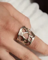 Anillo ancho de diseño orgánico y calado, con apariencia de red o magma solidificado.