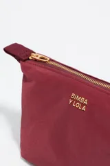 Neceser de diseño trapecio confeccionado en nylon color bordó, con cierre superior y logo de la marca estampado en dorado en el frente.