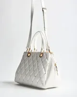 Cartera tipo bolso de mano XL color blanco de símil cuero con diseño matelassé romboidal, tachas metálicas doradas, doble asa corta y correa bandolera regulable y desmontable. Incluye herrajes dorados y logo metálico de la marca en el frente.