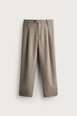 Pantalón relaxed fit de hombre color marrón con textura estructurada, cintura con pliegues frontales, bolsillos laterales y cierre frontal con cremallera y botón.