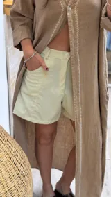 Short de lino en color celeste, con diseño de tiro alto, cierre frontal con botón a la vista y costuras decorativas verticales en el frente.