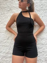 Mono corto negro con escote asimétrico halter y detalle de lazo al cuello.