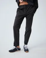 Pantalón negro de corte slim, confeccionado en lana y poliéster con elastano. Presenta cintura elastizada, cierre frontal con snap metálico, bolsillos laterales con cierre metálico y cierre en la botamanga.