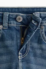 Jean de denim azul con leve stretch, corte ajustado de cintura a cadera y acampanado desde la rodilla al bajo. Modelo de tiro bajo con cierre y botón, bolsillos delanteros abiertos y bolsillos traseros con solapa y botón.
