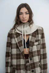 Chaqueta de corte sastre con estampado de cuadros en tonos marrones y beige, con solapas clásicas y cierre frontal con botones.