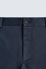 Pantalón chino de corte regular fit, confeccionado en tejido de algodón con elasticidad. Presenta bolsillos frontales, bolsillos traseros de vivo y cierre frontal con cremallera y botón.