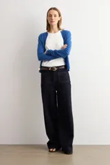 Cardigan de punto azul con cuello redondo, manga larga y cierre frontal abotonado con pequeños botones al tono.