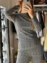 Remera de manga larga con brillos, cuello redondo y corte recto, confeccionada en tejido texturizado en tonos gris y negro.