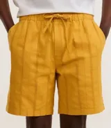 Bermuda recta de playa en color blanco roto, confeccionada en algodón texturizado con efecto de rayas verticales. Posee cintura elástica con cordón ajustable.