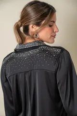 Camisa color crema de satén italiano con cuello clásico, cierre frontal con botones y mangas largas. Presenta apliques de strass en cuello, solapa y puños.